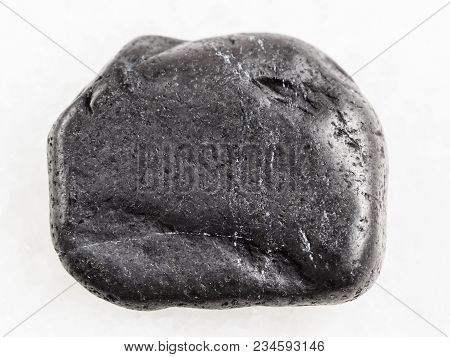 Macro Shooting Of Natural Mineral Rock Specimen - Tumbled Shungite Gemstone On White Marble Backgrou