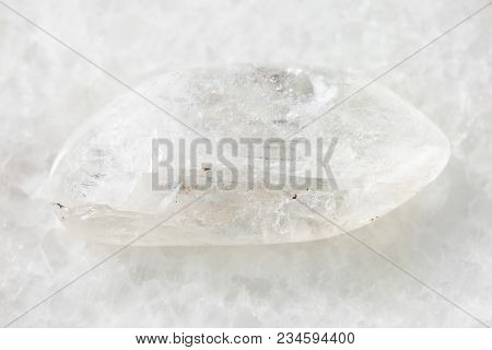 Macro Shooting Of Natural Mineral Rock Specimen - Tumbled Natrolite Gemstone On White Marble Backgro