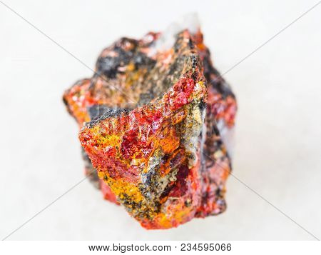 Macro Shooting Of Natural Mineral Rock Specimen - Raw Realgar Crystals On Stone On White Marble Back