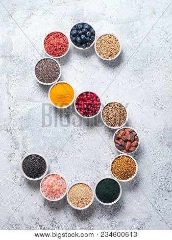 Above View Of Various Superfoods In Smal Bowl In Form S Letter On Gray Background. Superfood As Chia
