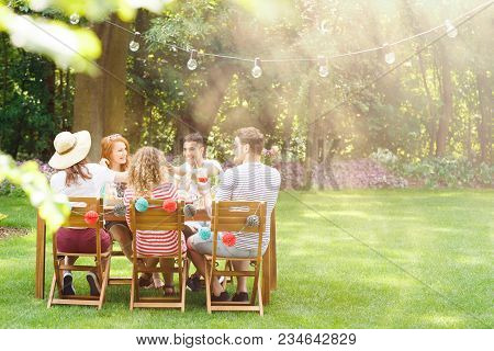 Group Of Smiling Friends Eating Lunch At  A Garden Party