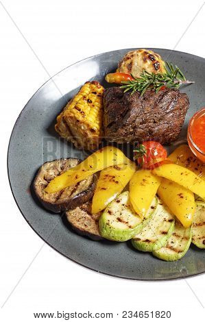 Fried Meat With Garnish Of Pepper, Zucchini, Tomato And Corn With Ajika Sauce Served On A Gray Plate