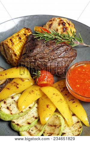 Fried Meat With Garnish Of Pepper, Zucchini, Tomato And Corn With Ajika Sauce Served On A Gray Plate