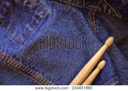 Two Drumsticks Lie On A Denim Jeans Textile