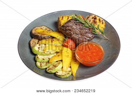 Fried Meat With Garnish Of Pepper, Zucchini, Tomato And Corn With Ajika Sauce Served On A Gray Plate