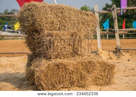 A Wall Of Rectangular Bales Of Straw Stacked In A Field Before Being Transported To Shelter