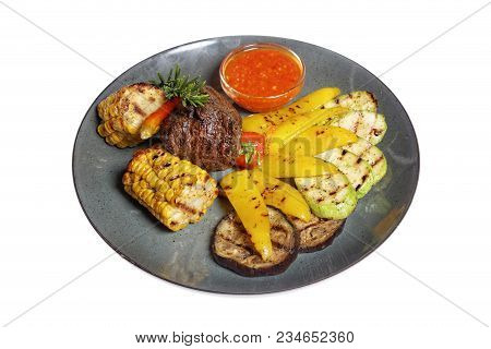 Fried Meat With Garnish Of Pepper, Zucchini, Tomato And Corn With Ajika Sauce Served On A Gray Plate