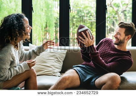 Young couple watching american football at home