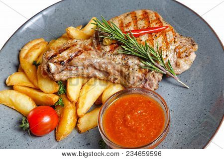 Fried Meat With Garnish Of Pepper, Zucchini, Tomato And Corn With Ajika Sauce Served On A Gray Plate