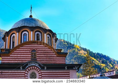 Rila Monastery, Bulgaria Church Dome And Cross Close-up And Autumn Mountain Trees At Background