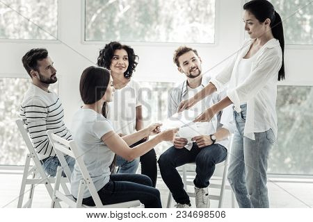 Interesting Teambuilding Activity. Smart Pleasant Young Woman Taking A Sheet Of Paper And Looking At