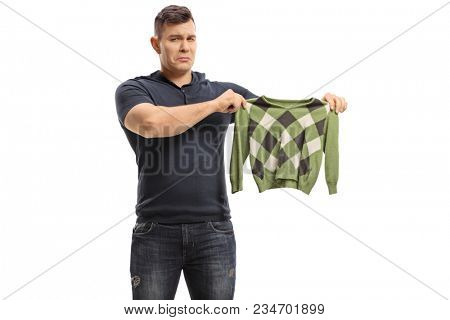 Upset young man holding a shrunken blouse isolated on white background