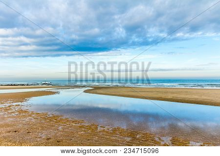 Beach At Sunset Rfelcting Clouds In Tidal Pool