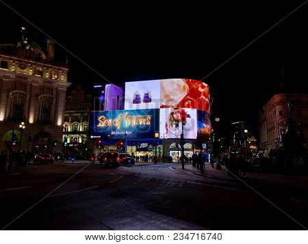 LONDON - APRIL 4, 2018: Tourists lit up at night by bright advertising illumination screens in Piccadilly Circus, Westminster, London, UK.