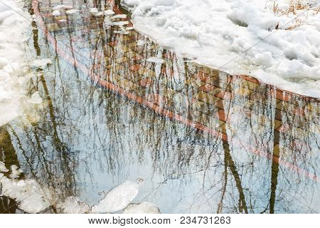 Flooding Of Tile Walkpath Due To Snow Melting And Rising Of Water Level. Blue Sky In Puddle Reflecti