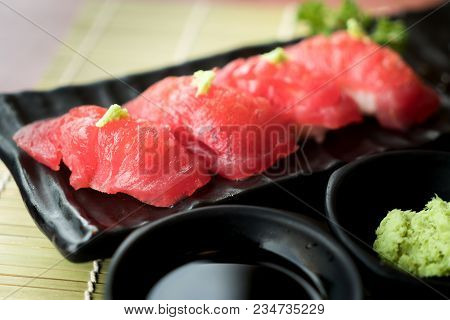 Tuna Sushi On Black Plate Along With Japanese Sauce And Green Leaf Decoration, Japanese Food, Close 
