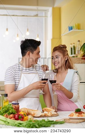 Cheerful Young Vietnamese Couple Drinking Wine When Cooking Dinner