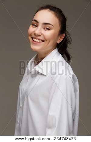 Beautiful Girl In A White Shirt Shows Emotions - Smile, Fun. On A Light Background.