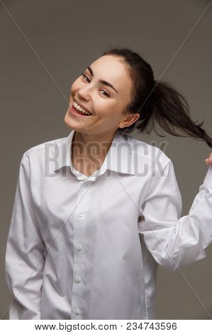 Beautiful Girl In A White Shirt Shows Emotions - Smile, Fun. On A Light Background.