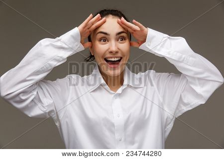 Beautiful Girl In A White Shirt Shows Emotions - Smile, Fun. On A Light Background.