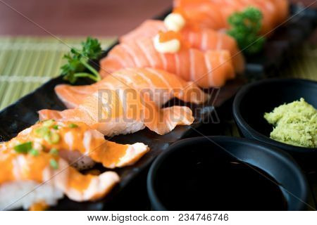 Mixed Salmon Sushi On Black Plate Along With Japanese Sauce And Green Leaf Decoration, Japanese Food