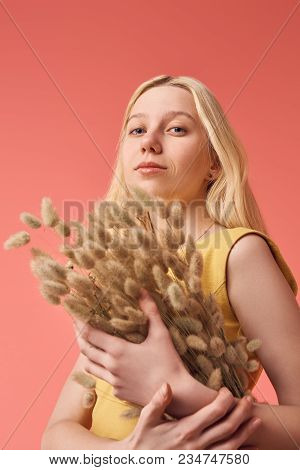 Beautiful Young Woman With Bouquet Of Lagurus Looking At Camera Isolated On Red