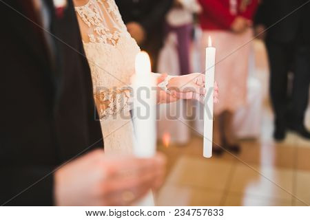 Bride And Groom Holding Candles In Church.