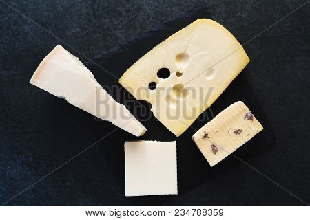 An Appetizing Solid Cheese On A Black Plate On A Gray Stone Background