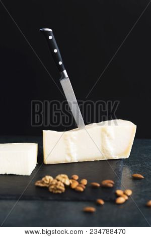 An Appetizing Solid Cheese On A Black Plate On A Gray Stone Background