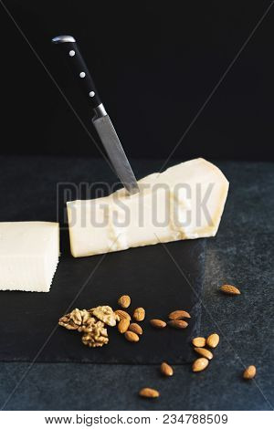 An Appetizing Solid Cheese On A Black Plate On A Gray Stone Background