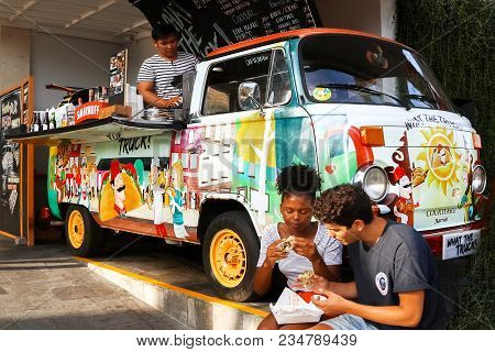 Indonesia, Bali, Seminyak - October 01, 2017: Guy And Girl Eating  And Talking  In A Cafe In The For