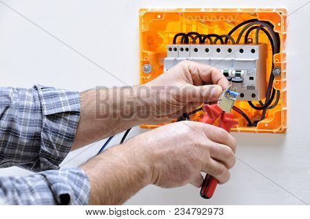 Electrician Technician Working On A Residential Electric Panel, Cuts The Cable With A Cable Cutter