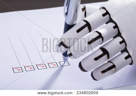 Close-up Of A Robot Hand Ticking Off Checkboxes On Document With Pen