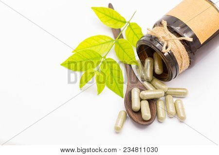 Green Herb Powder Capsules On Wooden Spoon Isolate On White