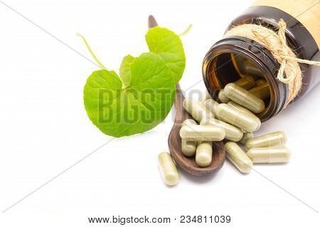 Green Herb Powder Capsules On Wooden Spoon Isolate On White