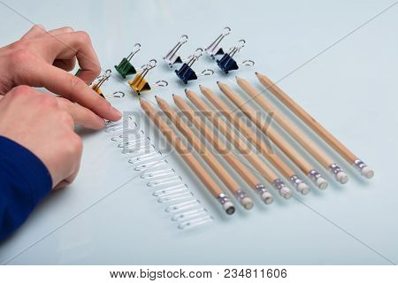 Elevated View Of A Human Hand Arranging Office Supplied In A Row