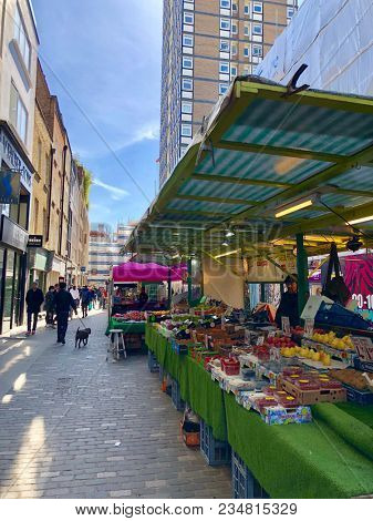 SOHO, LONDON - APRIL 5, 2018: Pedestrians at a market selling food, flowers, fruit and vegetables on Berwick Street in Soho, London, UK.