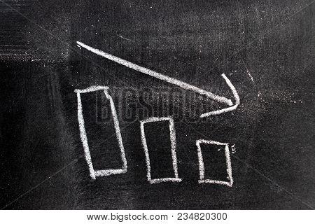 White Chalk Hand Drawing In Bar Chart With Downtrend Arrow Shape On Blackboard Background