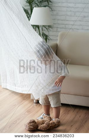 Child Playing With Curtain In Living Room