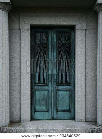 An Aged Double Door Entry Way Surrounded By Marble Walls And Pillars.