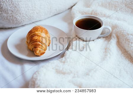 Big White Morning Cup Of Coffee And Crossant In Bed With Pillow And Cosy Blanket.