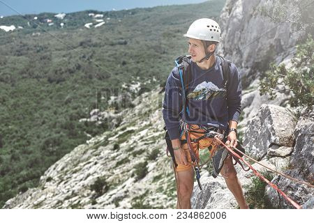 Man Rock Climber Climbed On The Cliff. Man Rock Climber On The Ledge Of The Cliff And Belays A Partn