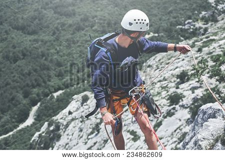Man Rock Climber Climbed On The Cliff. Man Rock Climber On The Ledge Of The Cliff And Belays A Partn
