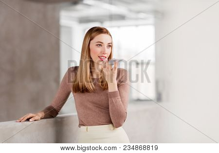 business people, technology and corporate concept - happy smiling businesswoman using voice command recorder on smartphone at office