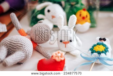 Three Handmade Knitted Hens And Rabbits On Beige Background As Easter Decoration