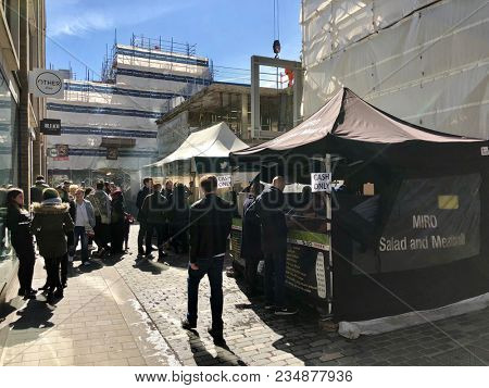 SOHO, LONDON - APRIL 5, 2018: Pedestrians at a market selling food, flowers, fruit and vegetables on Berwick Street in Soho, London, UK.