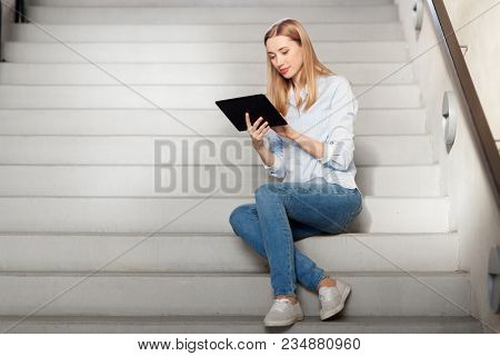 technology, business and corporate concept - woman or student with tablet pc computer sitting on stairs