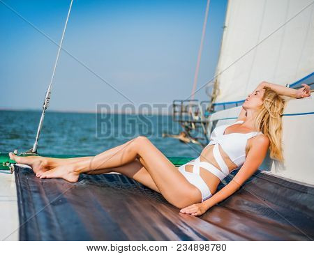 Woman In Fashion White Swimsuit Sitting On Yacht