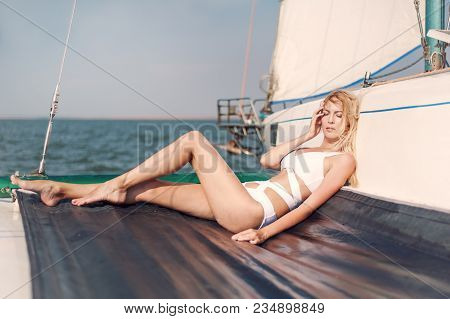 Woman In Fashion White Swimsuit Sitting On Yacht