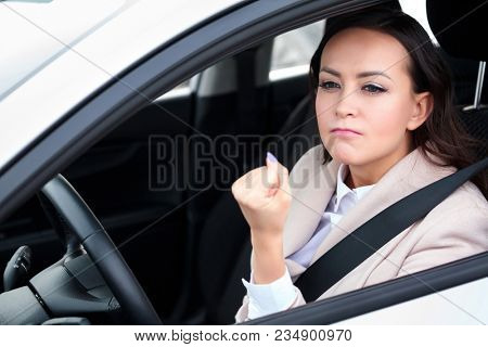 Boorishness on the road. Young woman is showing her fist to someone